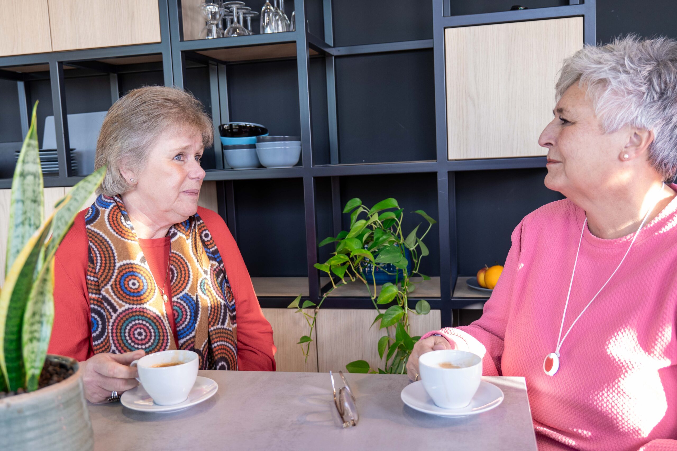 Twee ouderen die gezellig aan tafel zitten
