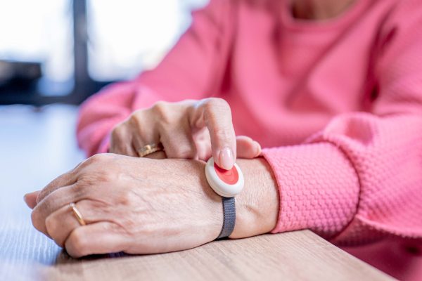 Een oudere mevrouw drukt valdetectie in haar handen